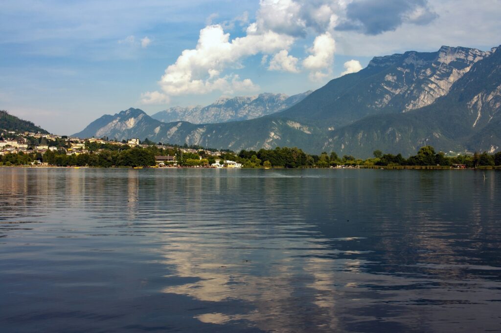 Walk on the lake of Levico. View of Levico Terme and the Dolomites