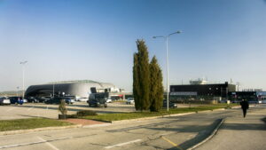 Exteriér terminálu Letiště Brno-Tuřany s nápisem Letiště Brno a parkovištěm před budovou
